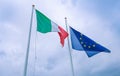 Waving fabric texture of the flag of italy and union europe on blue sky with clouds, concept Royalty Free Stock Photo