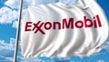 Waving flag with Exxon Mobil logo against sky and clouds. Editorial 3D rendering