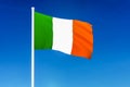 Waving flag of Ireland on the blue sky background
