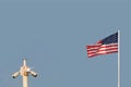 Waving flag of United States of America against pastel light blue color sky and metal pole with three CCTV cameras. Copy space