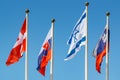Waving flags of different countries on flagpoles on a blue sky background Royalty Free Stock Photo
