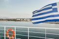 Waving Greek flag and orange lifebuoy hanging on white metal safety rail at Kos island view background Royalty Free Stock Photo