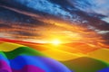 Waving LGBT pride flag on sunset sky with flying birds, rainbow flag background. Multicolored peace flag movement.