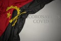 waving national flag of angola on a gray background with text coronavirus covid-19 . concept Royalty Free Stock Photo