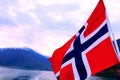 Waving Norwegian flag on the fjord surrounded by mountains background Royalty Free Stock Photo