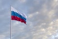 Waving Russian flag against a blue sky with clouds and empty space for text. Room for text. Royalty Free Stock Photo