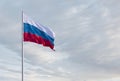 Waving Russian flag against a blue sky with clouds and empty space for text. Room for text.