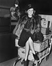 Waving woman sitting on pile of luggage Royalty Free Stock Photo