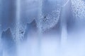 Wavy bizarre diagonal frosty pattern on blue frozen winter window.