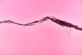 Wavy clear fresh water on pink background with drops and bubbles. Royalty Free Stock Photo