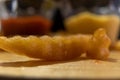 Wavy fry on wooden surface with blurry ketchup and melted cheese as background