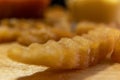 Wavy fry on wooden surface with blurry ketchup and melted cheese as background