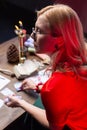 Blonde-haired diviner with wavy hair practicing at home sitting at the table