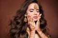 Wavy hair. Portrait of beautiful woman with indian jewelry. Young brunette model with Traditional Indian golden bijouterie set. Royalty Free Stock Photo