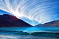 Wavy lake among mountains under swirling sky