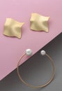 Wavy shape earrings pair and bracelet with pearl on pink and gray paper