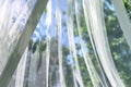 A wavy surface of a chiffon fabric against a blurry green trees and blue sky outdoor background Royalty Free Stock Photo