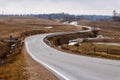 Wavy tarmac road framed with brown meadows at early spring. Royalty Free Stock Photo