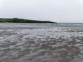 Wavy wet sand on the shore of a cold sea. Seaside landscape on a cloudy day. Beautiful patterns on the sand near body of water Royalty Free Stock Photo