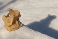 A wax angelic face set in snow has a sad appearance as new snow appears outside. Text space.