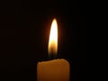 wax burning candle in a dark room with yellow plamy focus on the flame Royalty Free Stock Photo