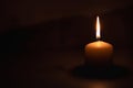 A wax candle is burning on a dark background. Flame of one candle at night close-up. Copy space. Royalty Free Stock Photo