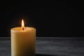 A wax candle is burning on a dark background. Flame of one candle at night close-up. Royalty Free Stock Photo