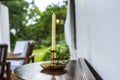 Wax candle in a gilded candlestick on a wooden table on the terrace of the house