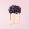 Wax for depilation of white pearl color and wooden stick spatula on pink background. Concept of waxing, smooth skin, bodycare, spa