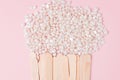 Wax for depilation of white pearl color and wooden stick spatula on pink background. Concept of waxing, smooth skin, bodycare, spa