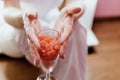 Wax in the form of granules for depilation of pink color is filled in a champagne glass. Waxing La depilation in hands holding a