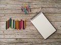 Wax pencils, paper clips and notebook on wooden background Royalty Free Stock Photo