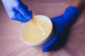 Wax for sugaring in a cosmetic jar in the hands of a master in a beauty salon.