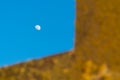 Waxing moon in the blue sky. Foreground is illuminated by the setting sun with warm colors. Abstract shot with geometric shapes.