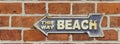 This way beach. Old rusty metal sign on a red brick wall. Blue with white lettering. Royalty Free Stock Photo