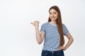 This way. Smiling young woman pointing finger left, showing sale place, product advertisement sideways, standing in Royalty Free Stock Photo