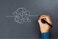 The way to business thinking success concept. A businessman hand drawing a white tangle line on blackboard