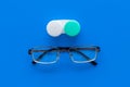 Way to improve vision. Contact lenses in container near glasses on blue background top view copy space Royalty Free Stock Photo
