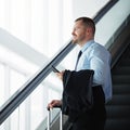 On the way to where the money is. a businessman traveling down an escalator in an airport. Royalty Free Stock Photo