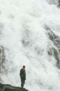 Wayfarer Man standing alone on cliff at big waterfall