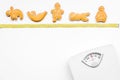 Ways for lose weight. Sport. Cookies in shape of yoga asans near scale and measuring tape on white background top view