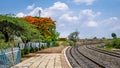 Wayside small railway station platform covered with colorful trees besides railway lines Royalty Free Stock Photo