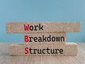WBS Work Breakdown Structure symbol. Brick blocks with words Work Breakdown Structure on beautiful blue background. Wooden table.