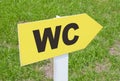 WC sign pointing direction on a green grass