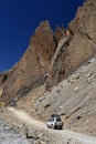 4WD Car on dirt road beside high rock mountain, Northern India Royalty Free Stock Photo