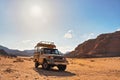 4WD off road vehicle parked in desert, backlight sun shines on mountains background - typical scenery of Wadi Rum, Jordan Royalty Free Stock Photo