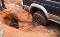 4wd vehicle driving over road with extreme holes and bumps, close up on rear wheel - roads are in very bad conditions in Royalty Free Stock Photo