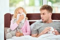 Weak immune system. Young father and daughter suffering from flu or cold, having runny noses while resting in bed Royalty Free Stock Photo