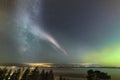 Weak Northern Lights on horizon and atmospheric phenomenon `STEVE` crossing Milky Way. Steve appears as a purple and green light