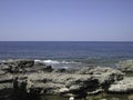 Weak waves gently wash the stones lying on the shallow bottom of the sea rocky shore in good weather